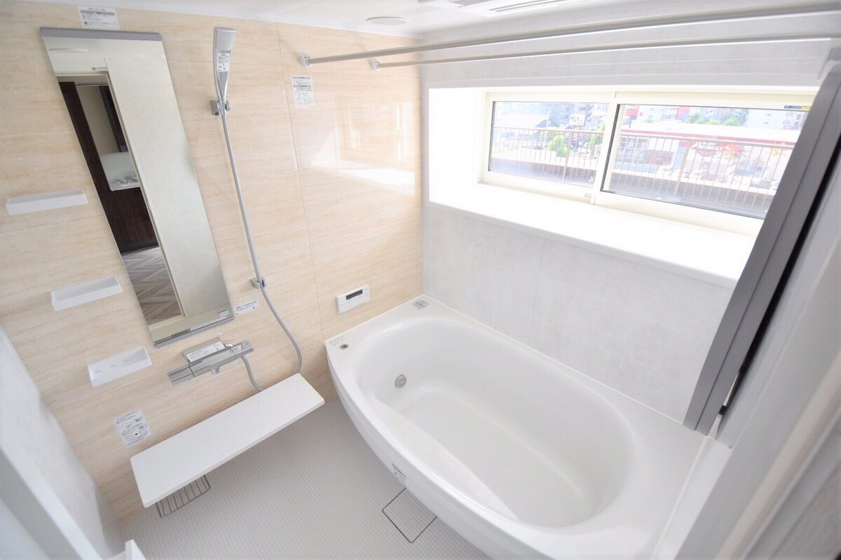 大きな窓とラウンド浴槽の明るいバスルーム