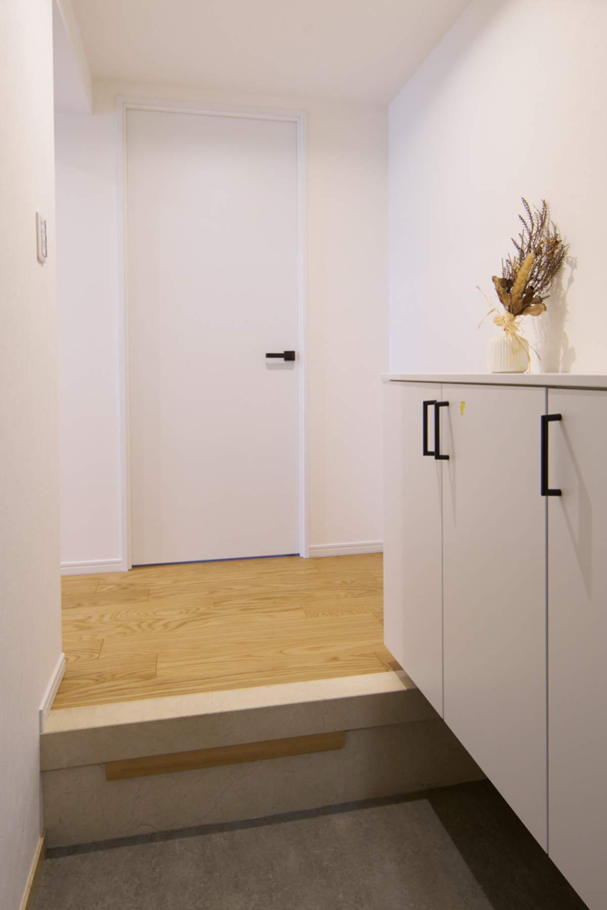 石目と木目が調和する、白い玄関