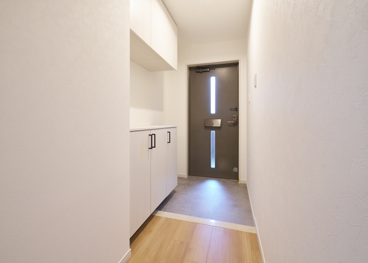 光射す玄関扉と、白い靴箱の空間