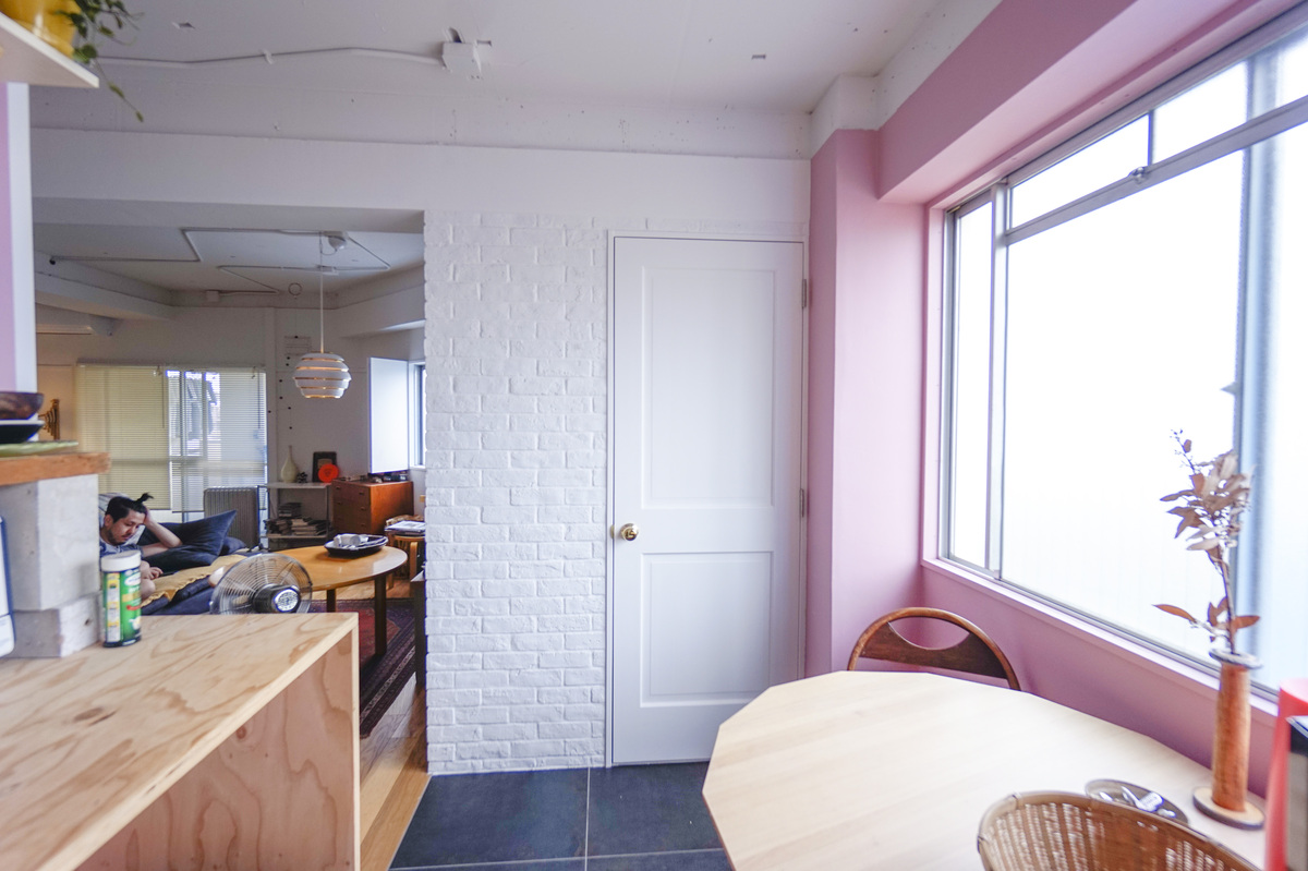 ピンクの壁と白レンガ、光差す食事席