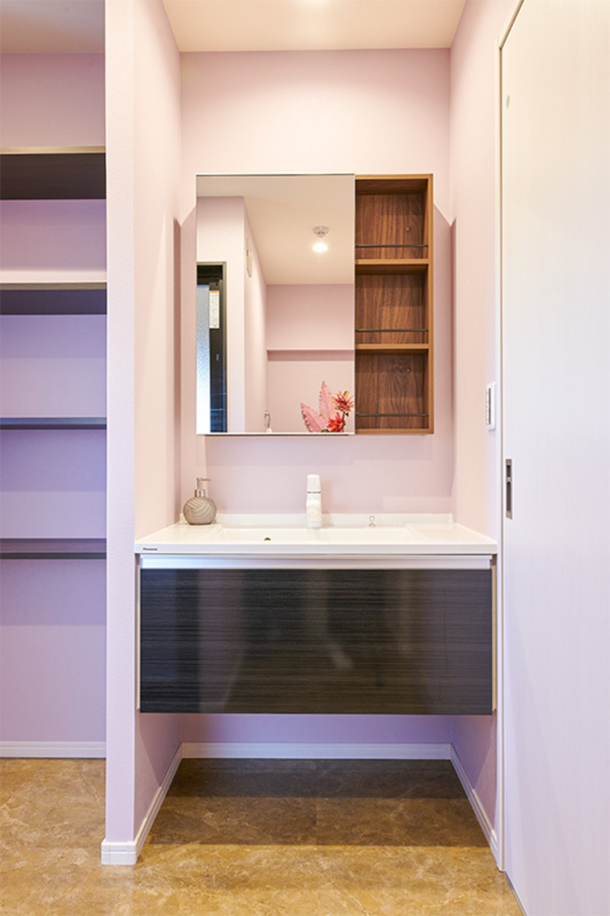 桃色の壁と黒木目が彩る洗面室
