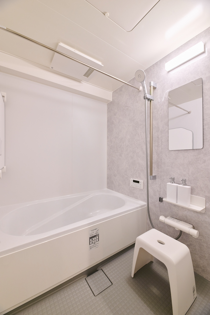 グレーの石目壁が落ち着く清潔な浴室			