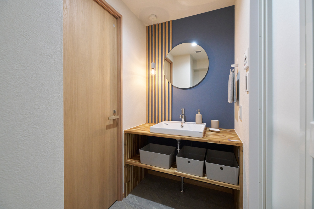 丸鏡と木格子が映える紺壁の洗面所			